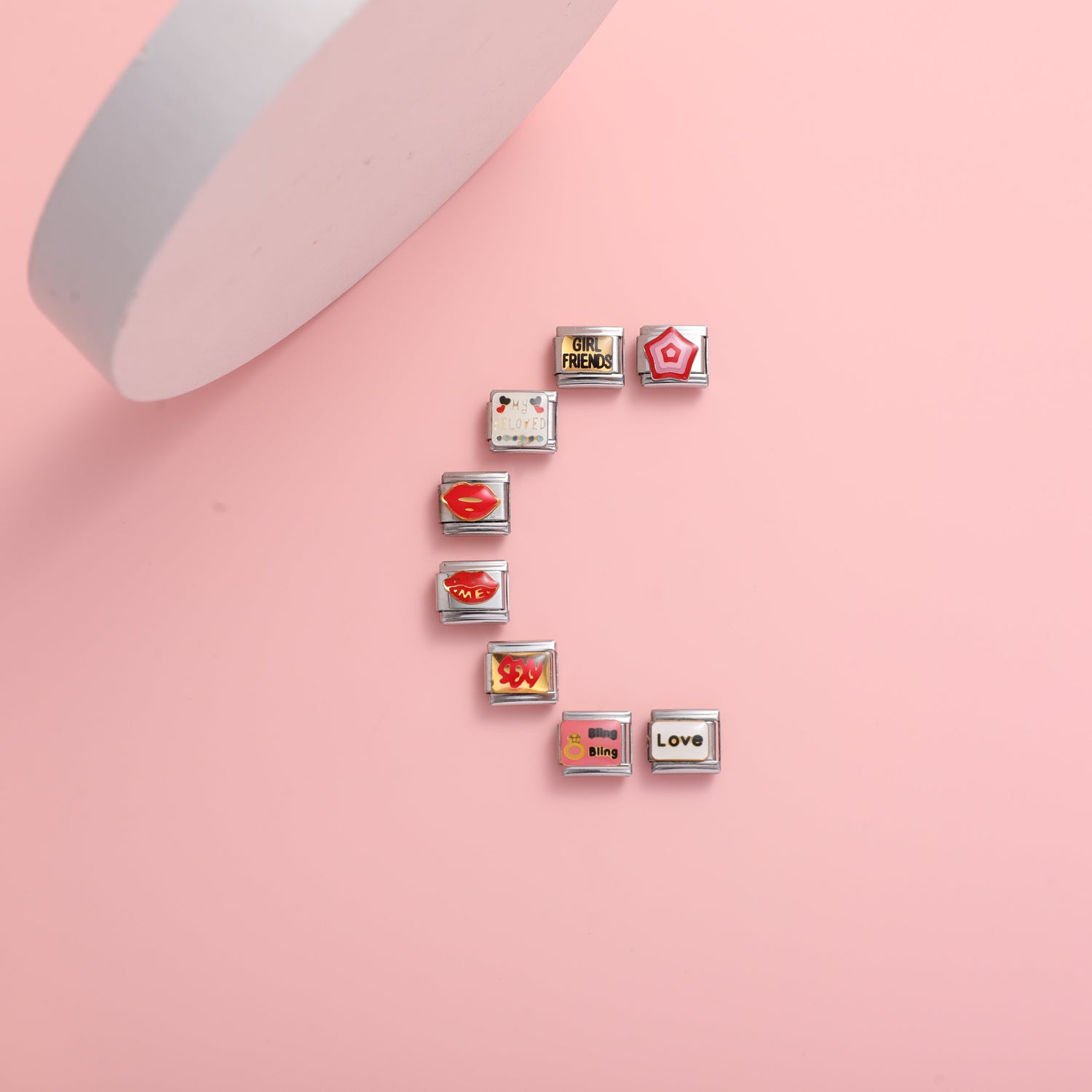 Italian charm bracelet love charms arranged in an S shape on a pink background featuring heart lips love and girlfriend themed Italian charms