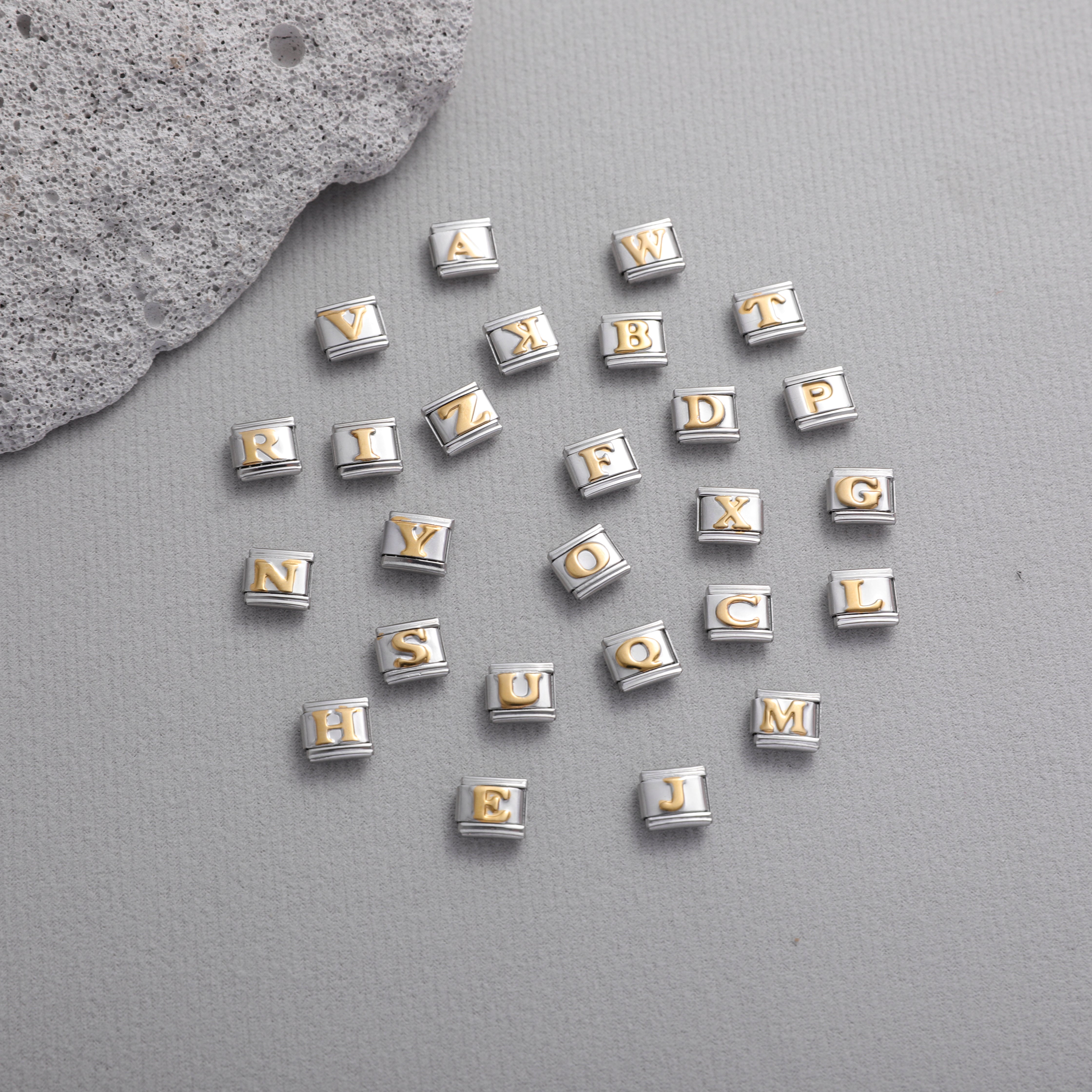Gold letter Italian charm bracelet charms scattered on textured background for DIY jewelry