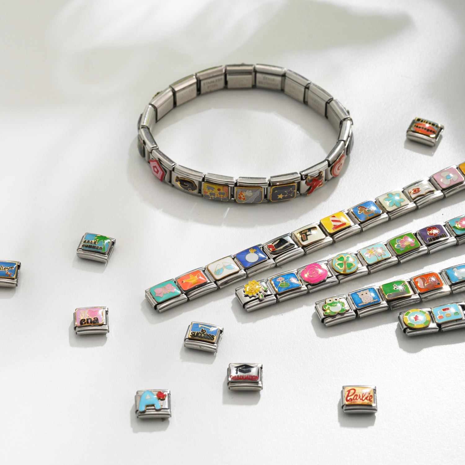 Colorful Italian charm bracelet designs with multiple modular charm links and loose charms on white background