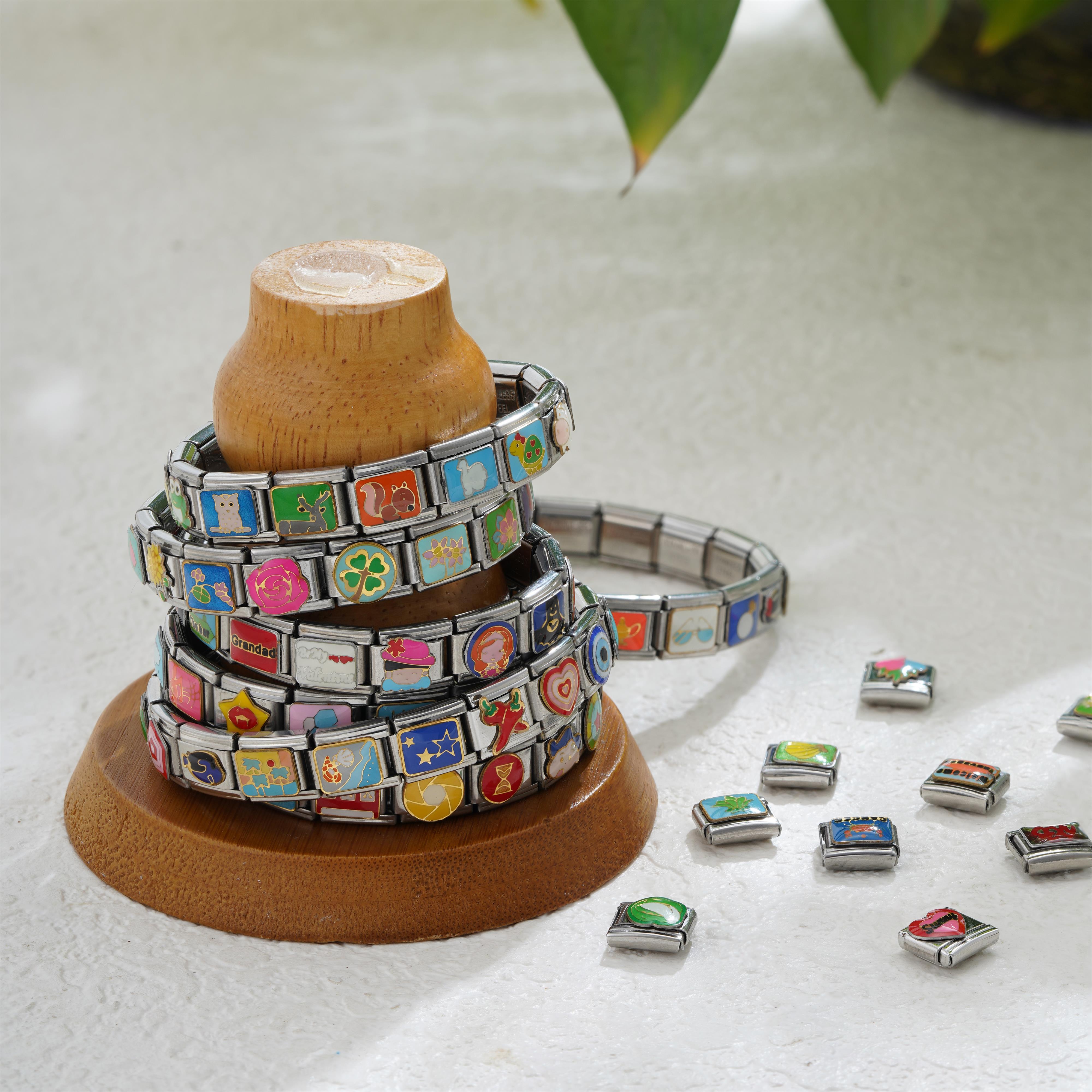 Stacked Italian charm bracelets with colorful animal, floral and symbol charms displayed on a wooden stand