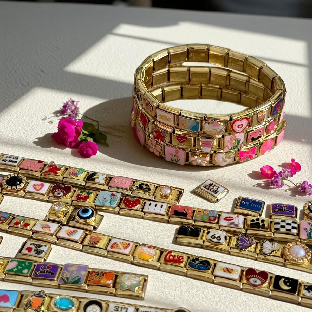 A cozy flat lay of Italian charm bracelets beside flowers, representing daily self-expression through jewelry