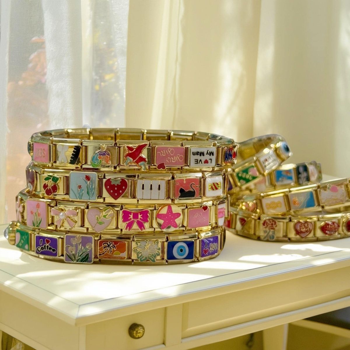 Italian charm bracelet collection displayed with gold links, showing a mix of hearts, letters, and travel charms
