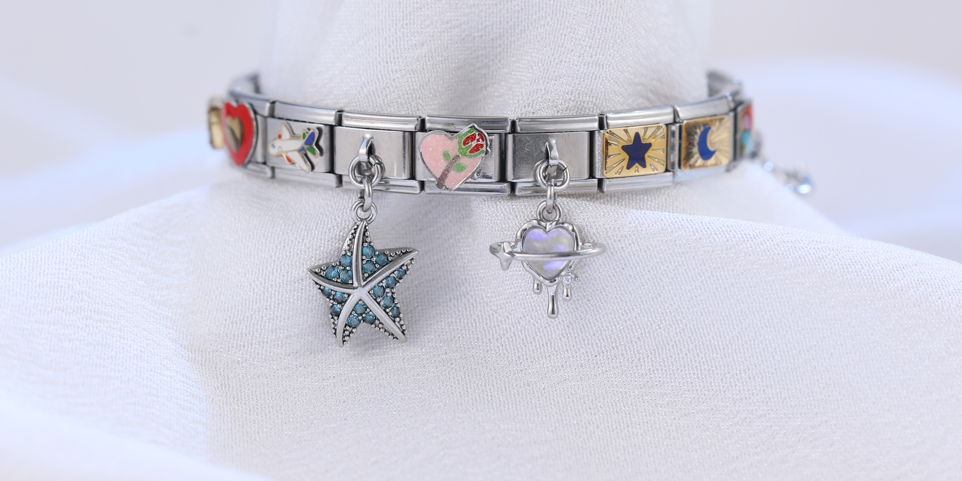 Italian charm bracelet with stainless steel modular links and dangling star and planet heart pendants shown in a clean close-up view