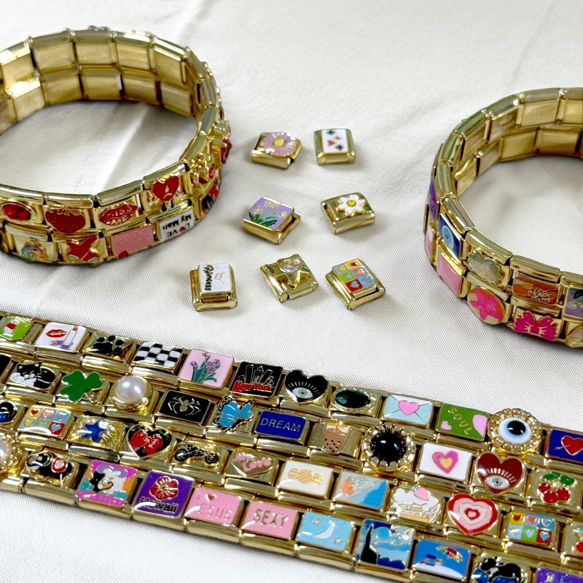 Close-up of Italian charm bracelets sparkling under natural light with gold and enamel links arranged by color