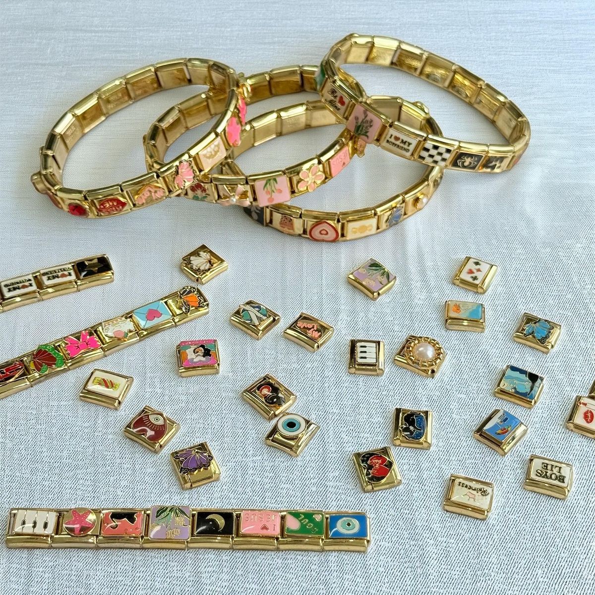 Gold Italian charm bracelet with heart and letter charms on soft fabric background