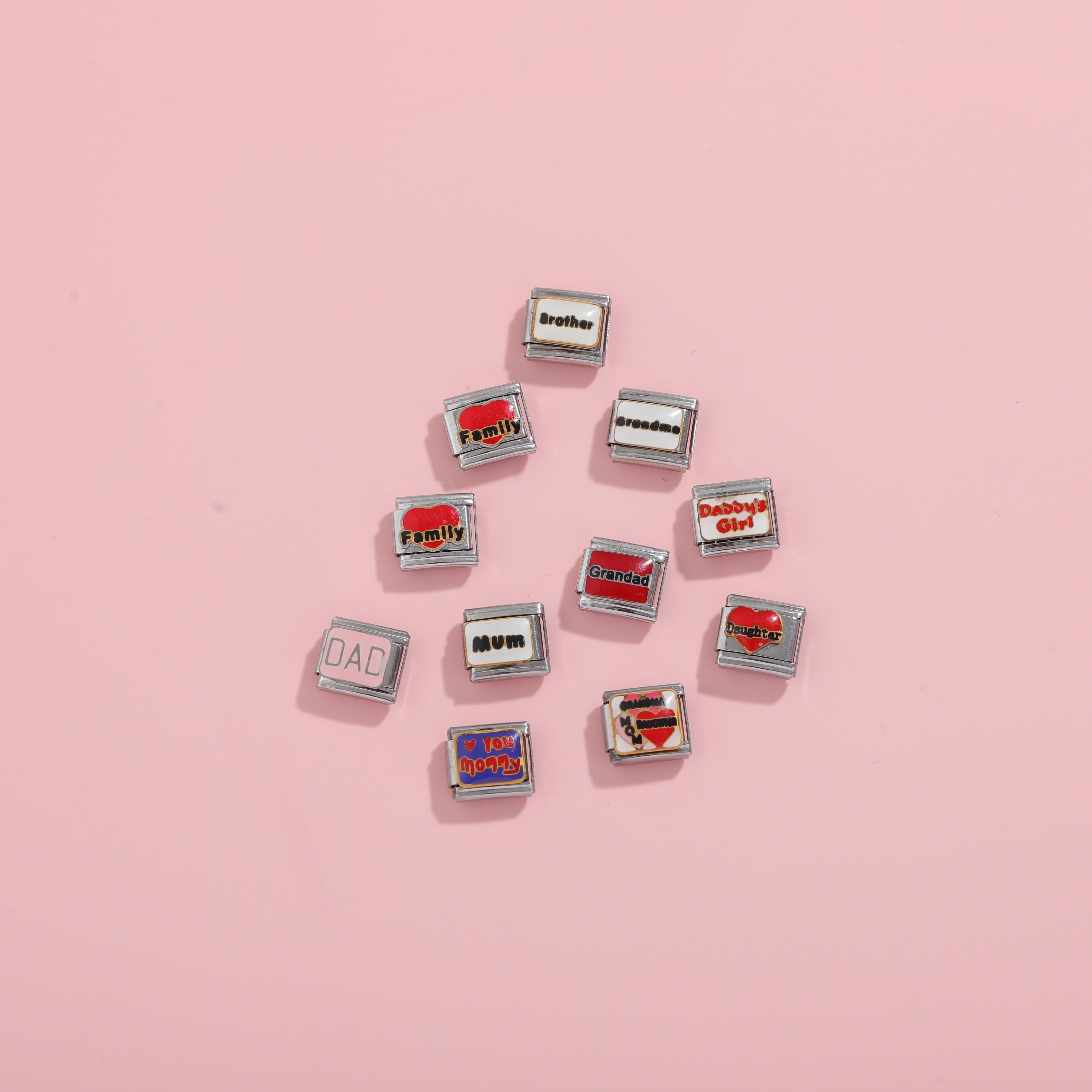 Family-themed Italian charm bracelet links with words like Mom Dad Brother and Daughter on a pink background