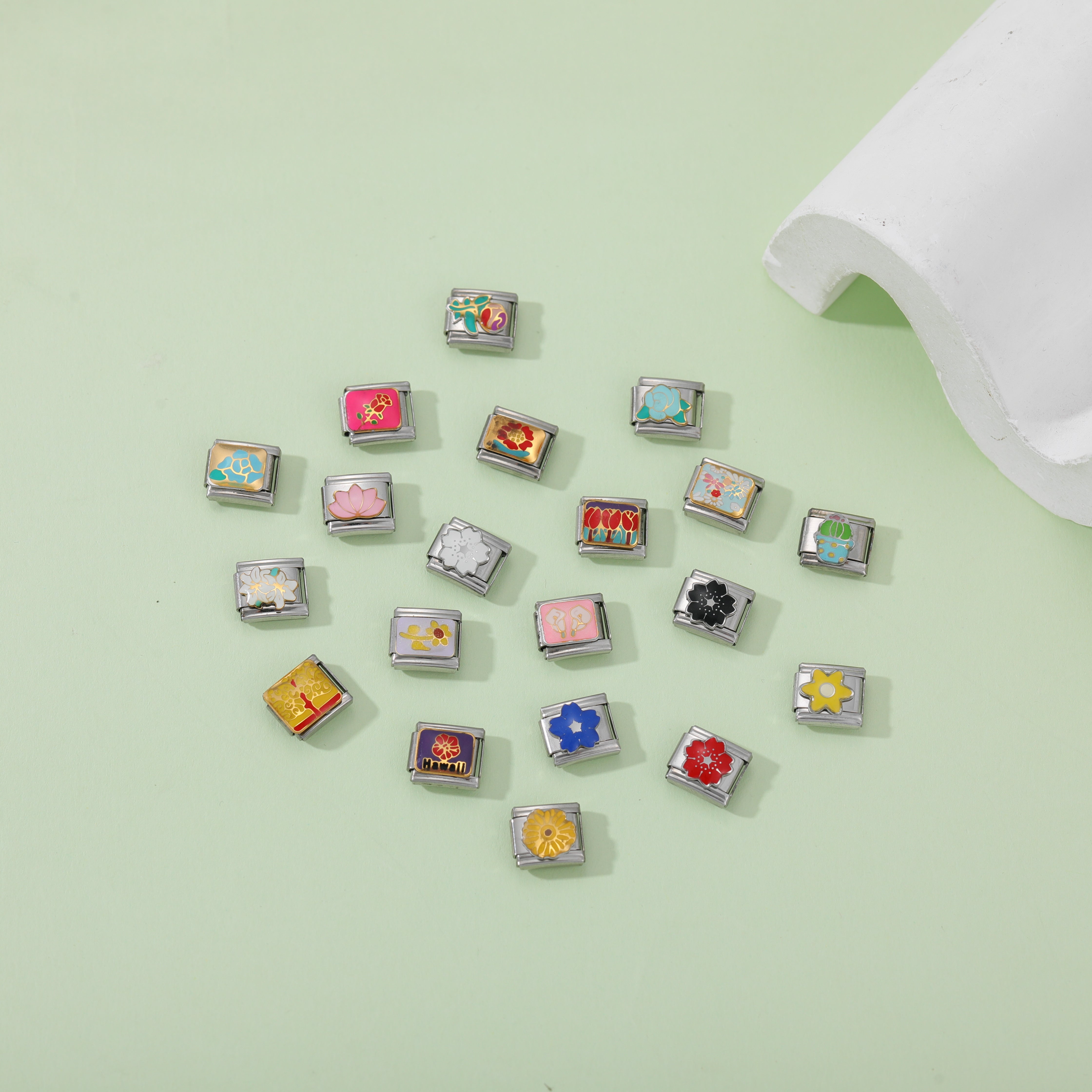 A scattered arrangement of stainless steel Italian charm links with colorful enamel floral designs