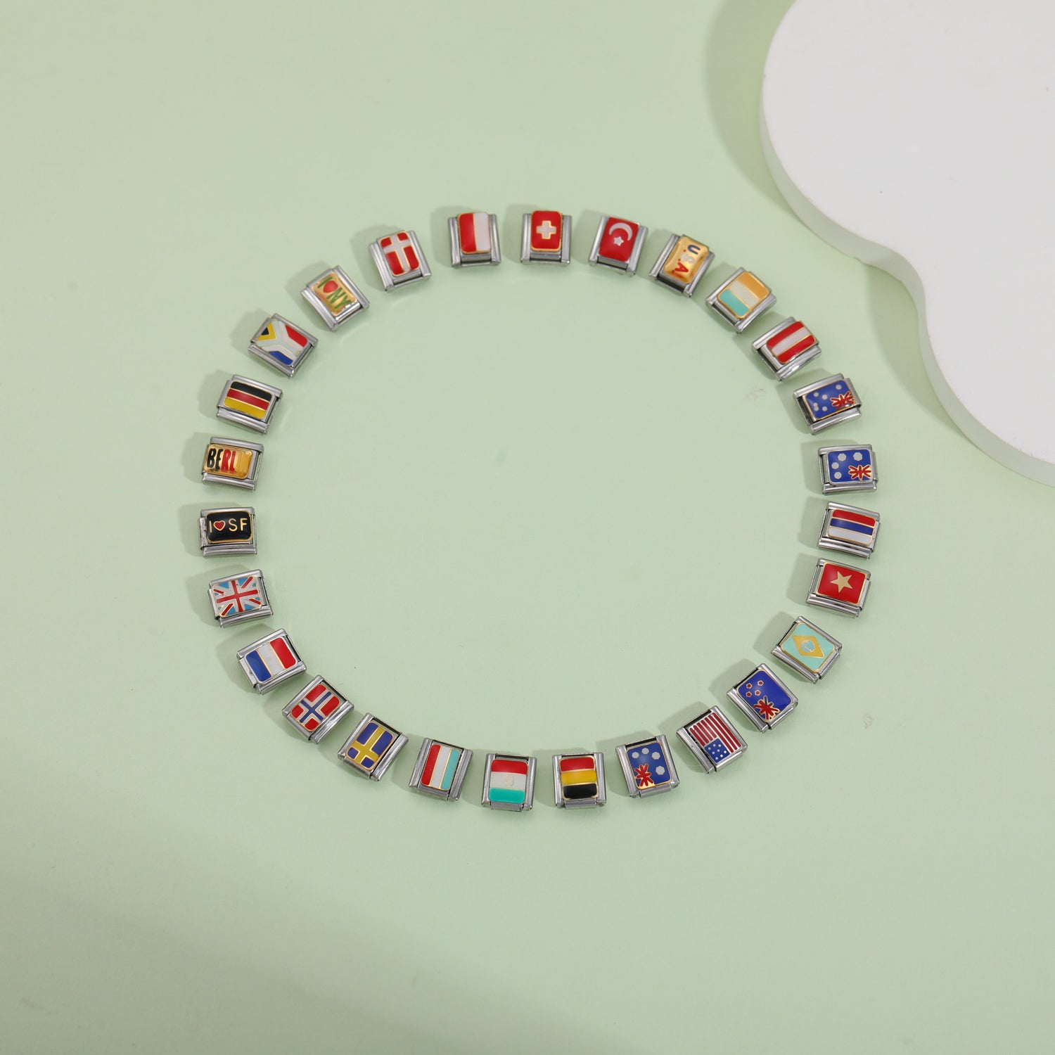 Italian charm bracelet with colorful country flag charm links arranged in a circle on green background