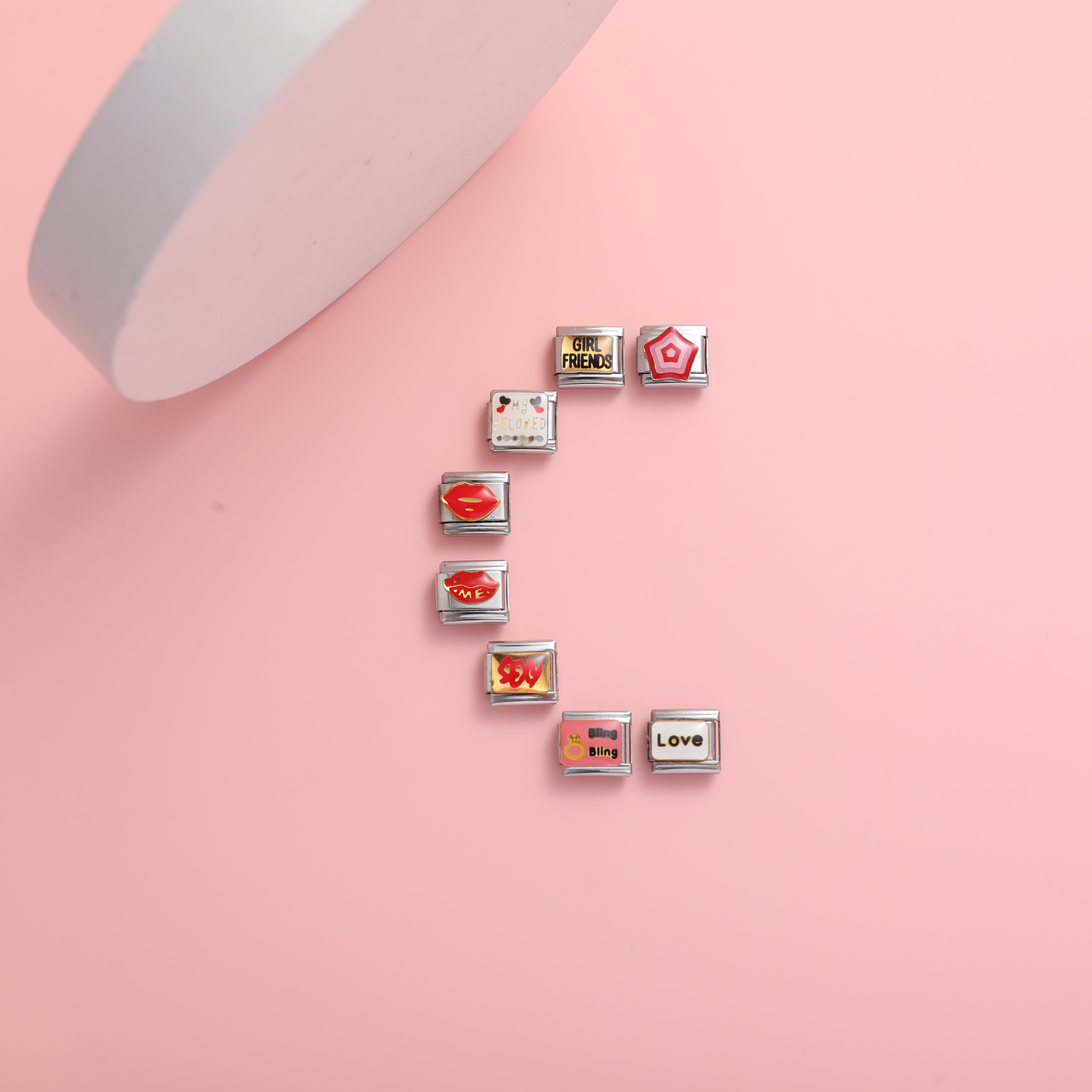 Italian charm bracelet love charms arranged in an S shape on a pink background featuring heart lips love and girlfriend themed Italian charms