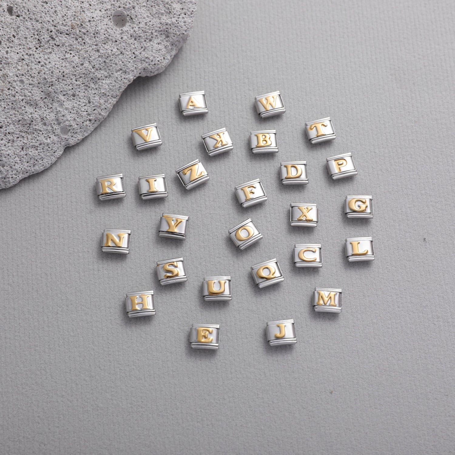 Gold letter Italian charm bracelet charms scattered on textured background for DIY jewelry