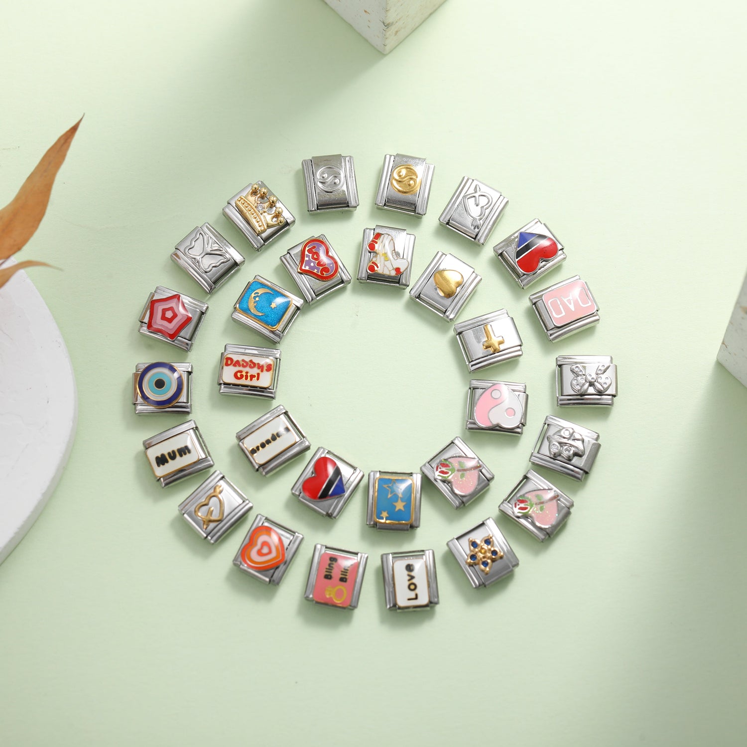 Colorful Italian charm bracelet links arranged in a circle on a pastel background, featuring hearts symbols and meaningful designs