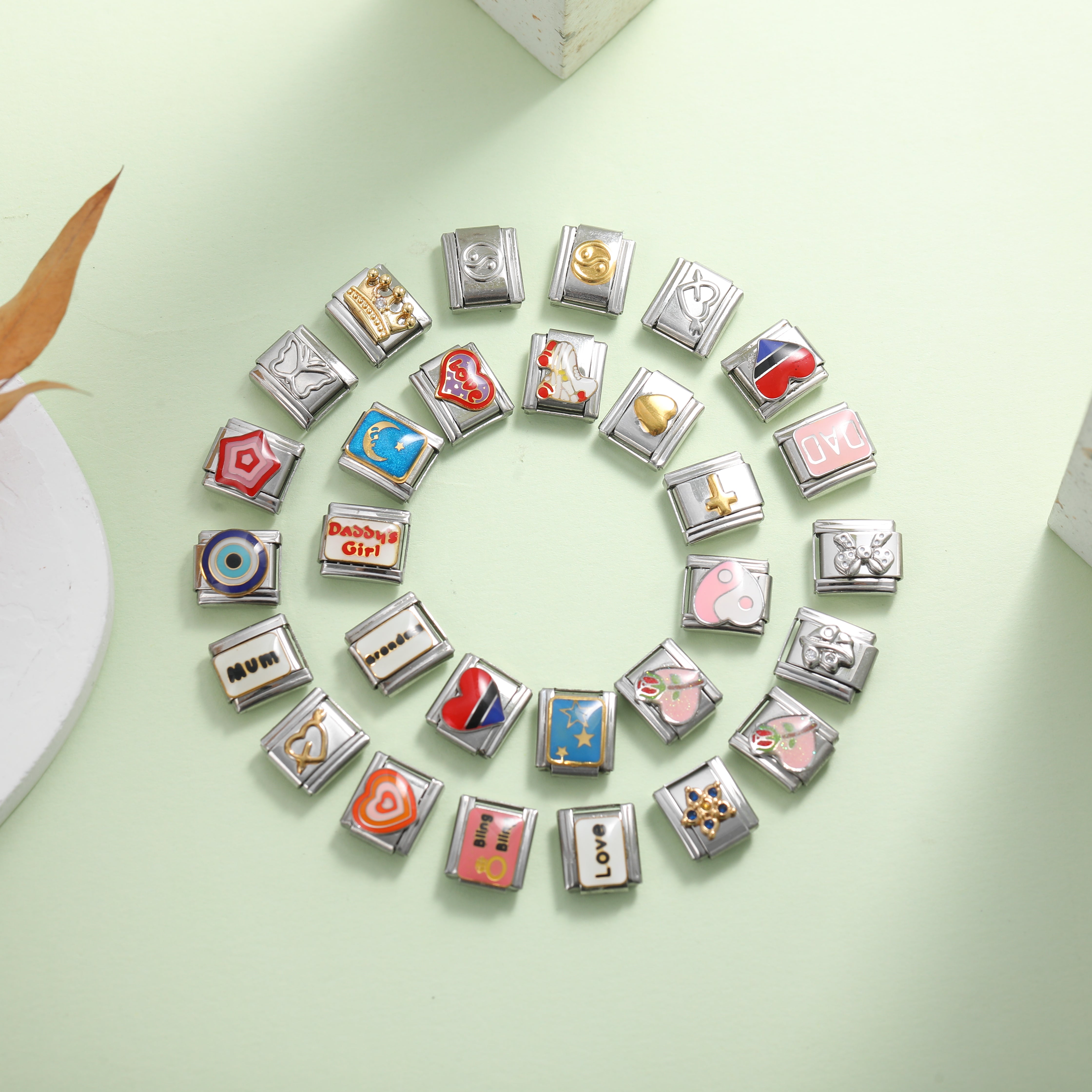 Colorful Italian charm bracelet links arranged in a circle on a pastel background, featuring hearts symbols and meaningful designs