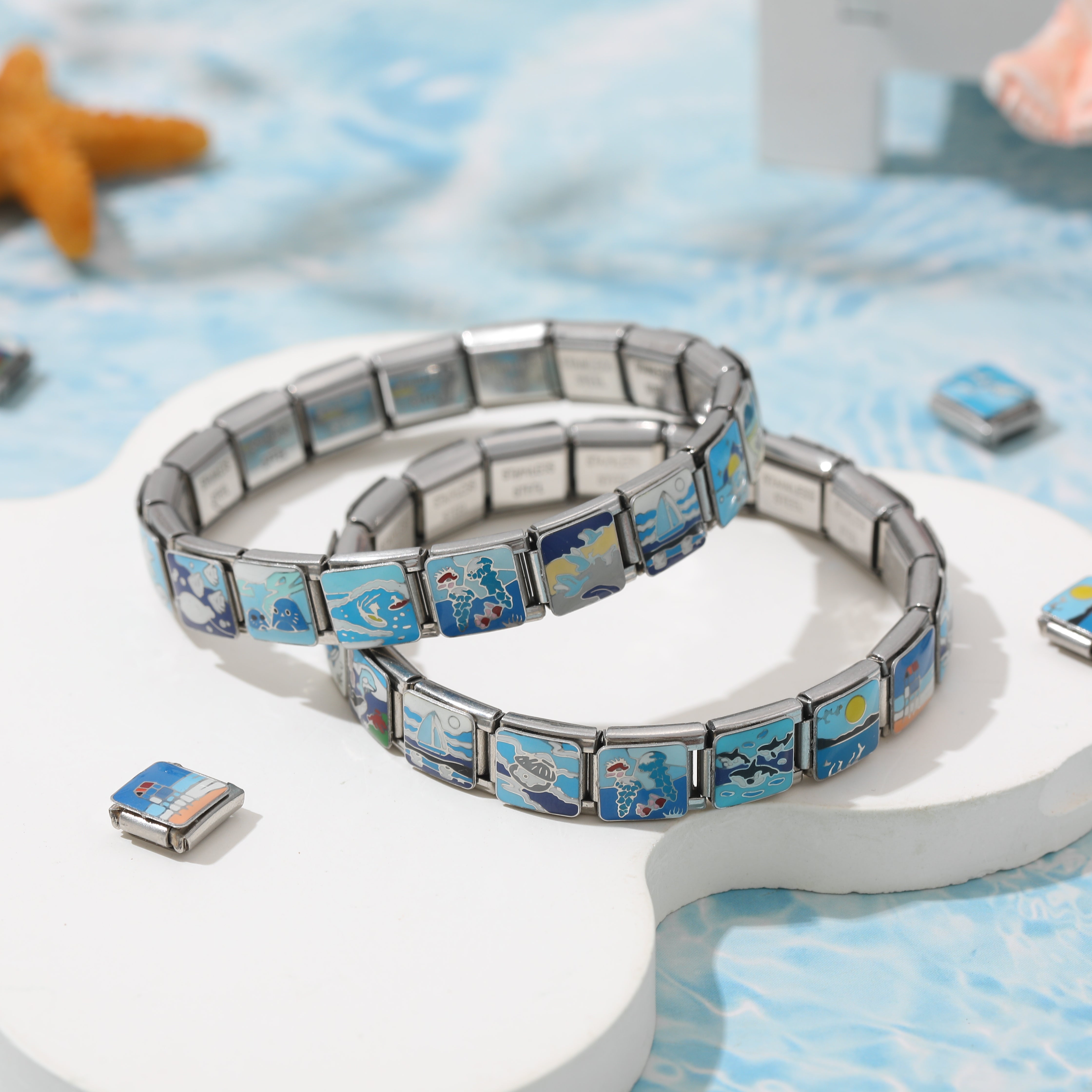 Double-layer Italian charm bracelet with ocean-inspired blue enamel charms displayed on a white platform
