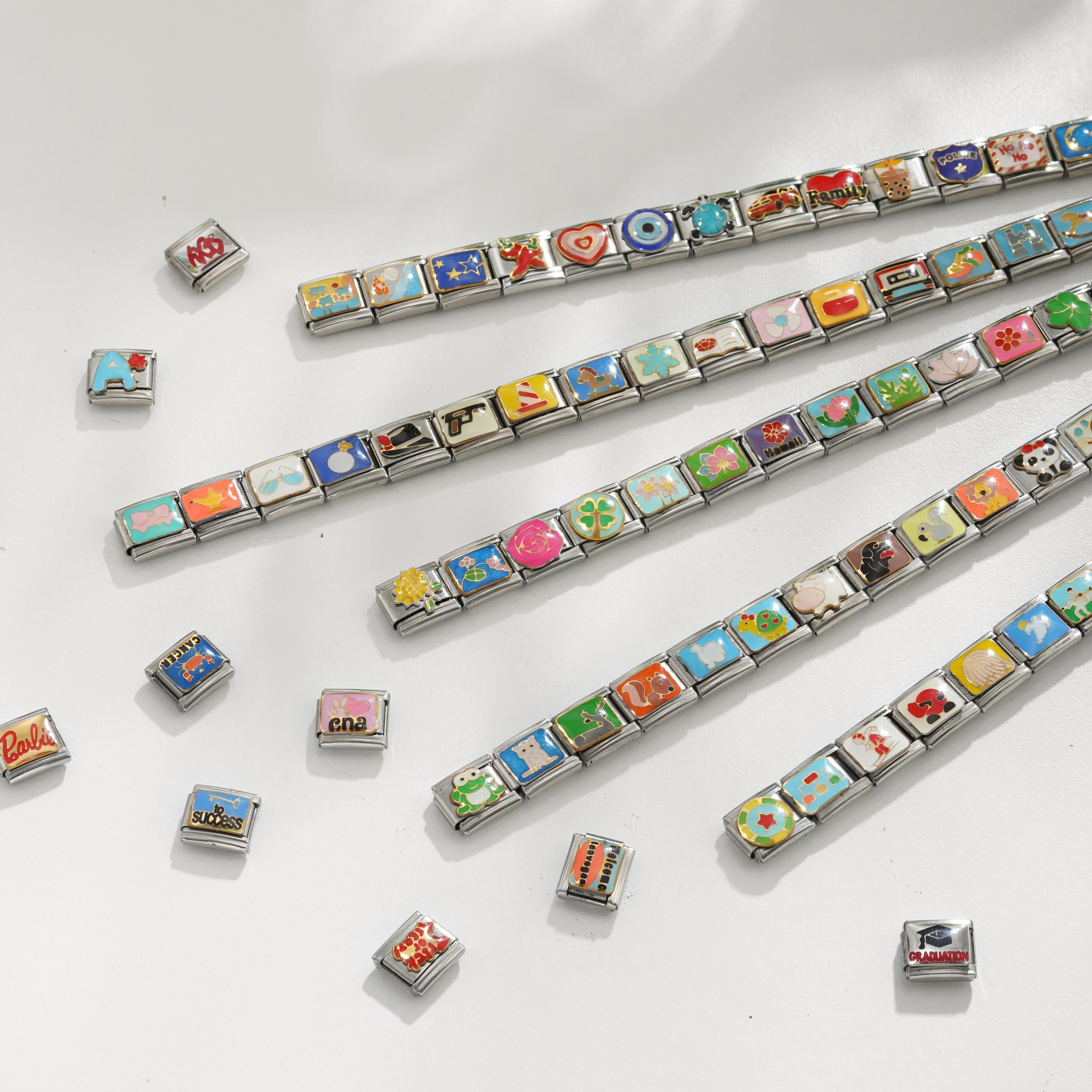Assorted Italian charm bracelets with colorful themed charm links scattered on a white surface