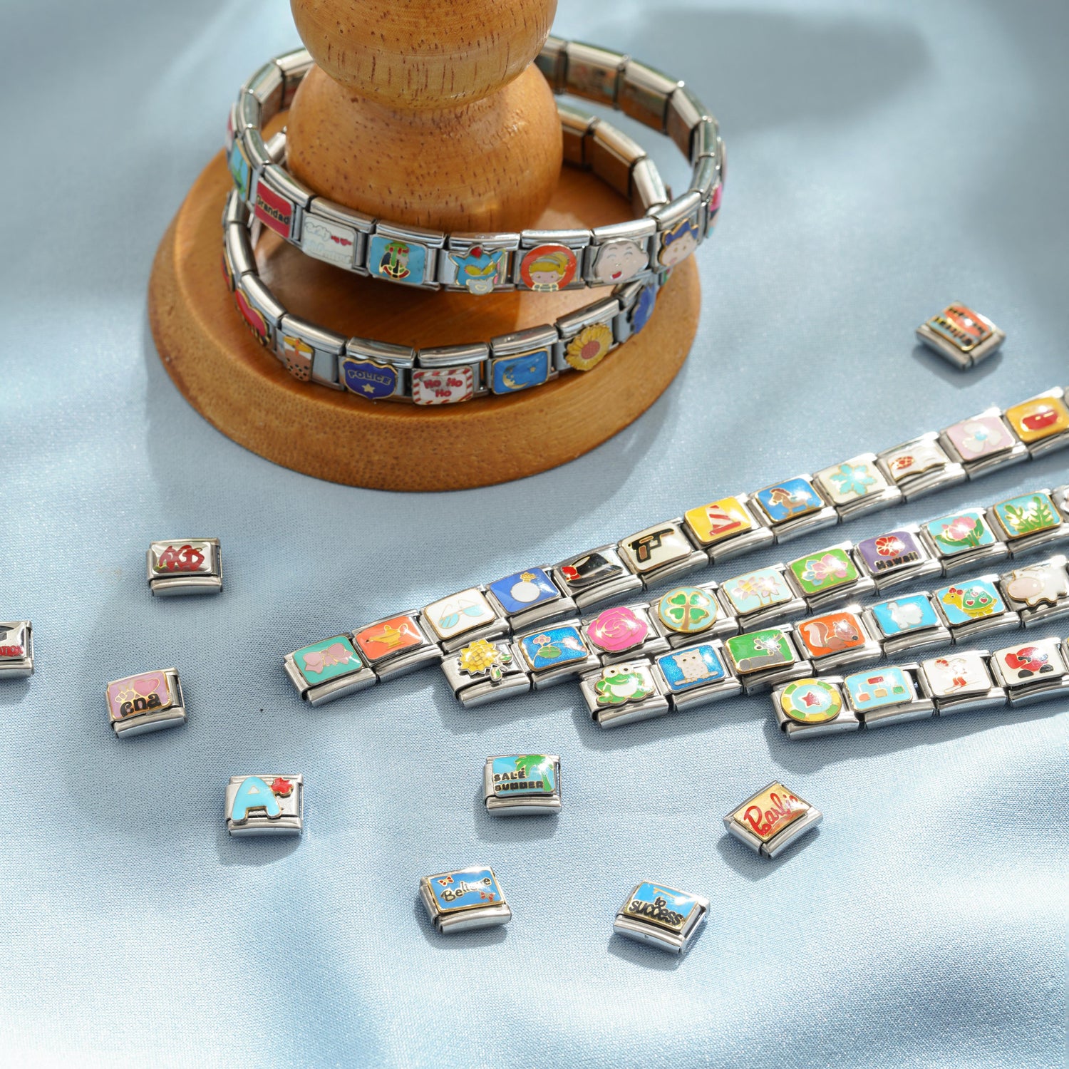 Italian charm bracelets displayed on a wooden stand with colorful charms and modular stainless steel links
