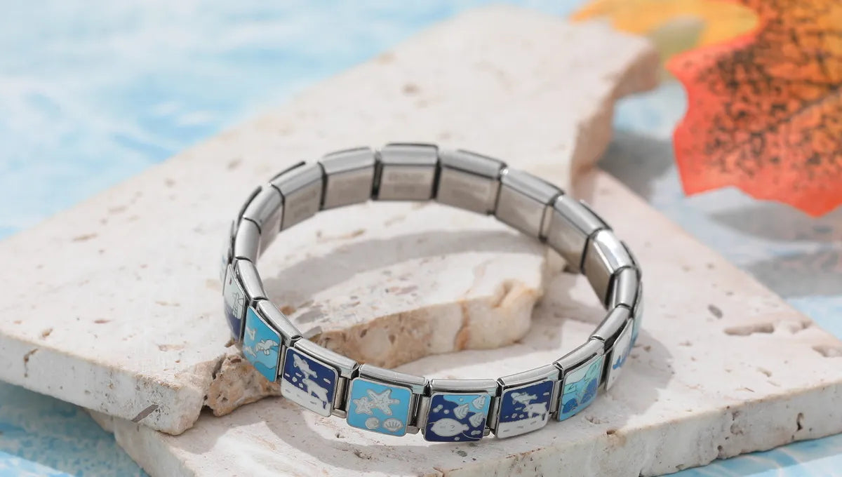 One fully assembled Italian charm bracelet displayed on a styled stand, showcasing modular stainless steel links